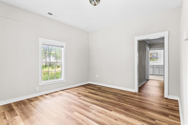 spare room with wood finished floors, visible vents, and baseboards