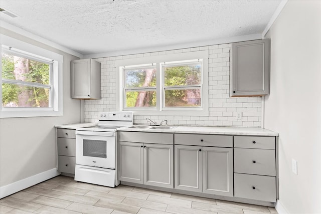 kitchen with visible vents, gray cabinetry, light countertops, decorative backsplash, and electric stove