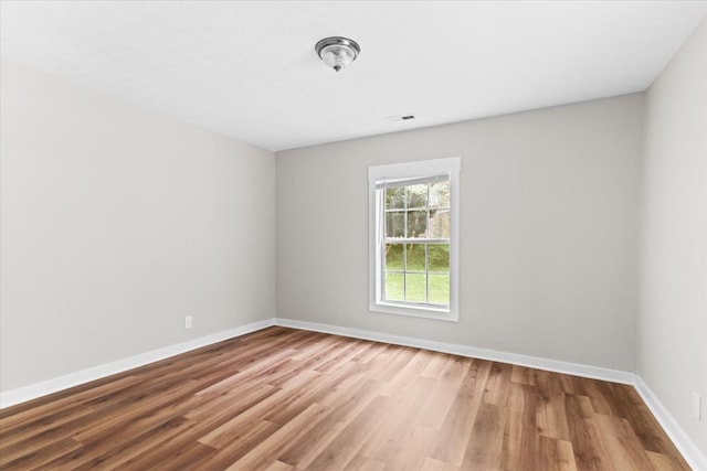 empty room with visible vents, baseboards, and wood finished floors