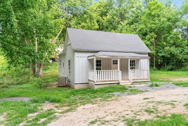 view of front of house with board and batten siding, central air condition unit, covered porch, and a shingled roof