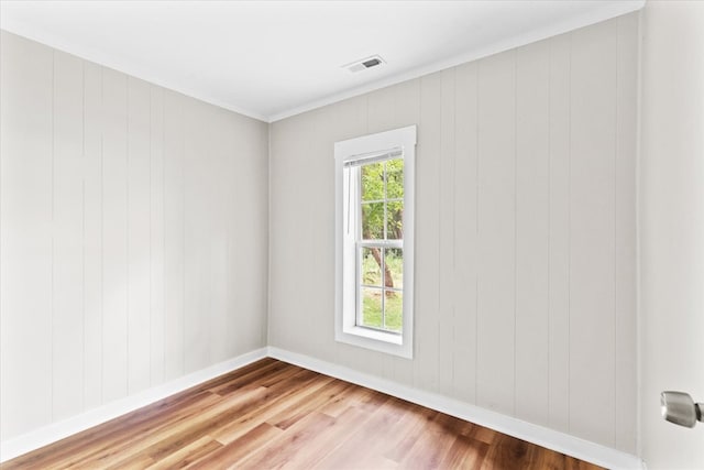 spare room with wood finished floors, visible vents, and baseboards