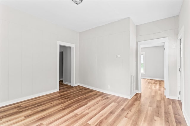 unfurnished room featuring baseboards, visible vents, and light wood finished floors