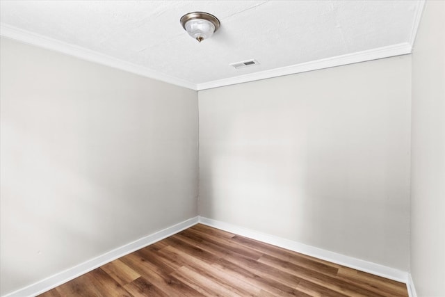 empty room featuring visible vents, baseboards, ornamental molding, wood finished floors, and a textured ceiling