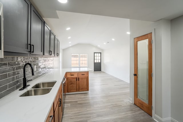 kitchen with light stone counters, tasteful backsplash, light wood-style flooring, brown cabinetry, and a sink