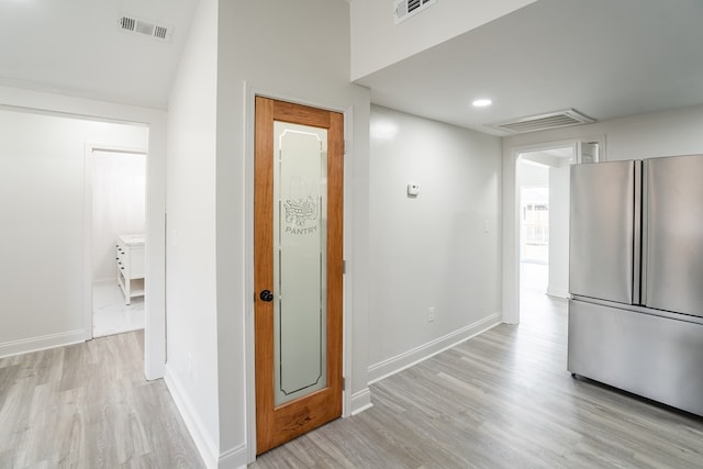 hallway with light wood-style floors and visible vents