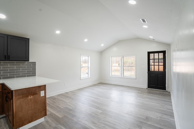 interior space featuring light wood-style flooring, visible vents, open floor plan, light countertops, and vaulted ceiling