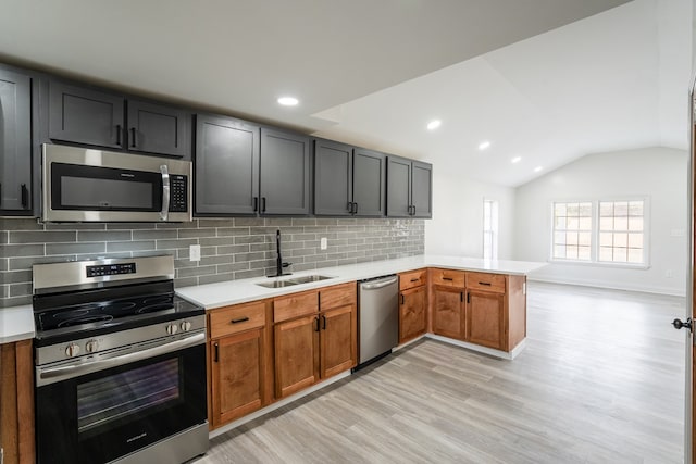 kitchen with stainless steel appliances, a peninsula, a sink, light countertops, and brown cabinetry