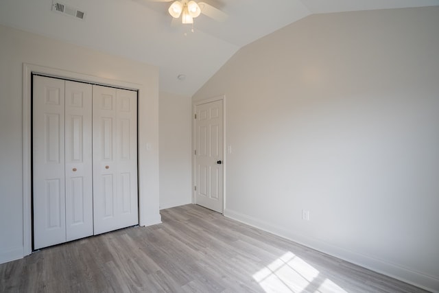 unfurnished bedroom featuring light wood finished floors, baseboards, visible vents, lofted ceiling, and a closet