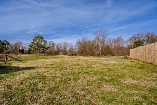 view of yard with fence and a rural view