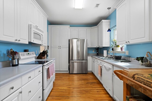 kitchen featuring visible vents, white appliances, white cabinetry, and a sink