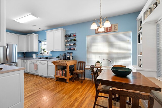 kitchen with open shelves, white dishwasher, freestanding refrigerator, white cabinets, and pendant lighting