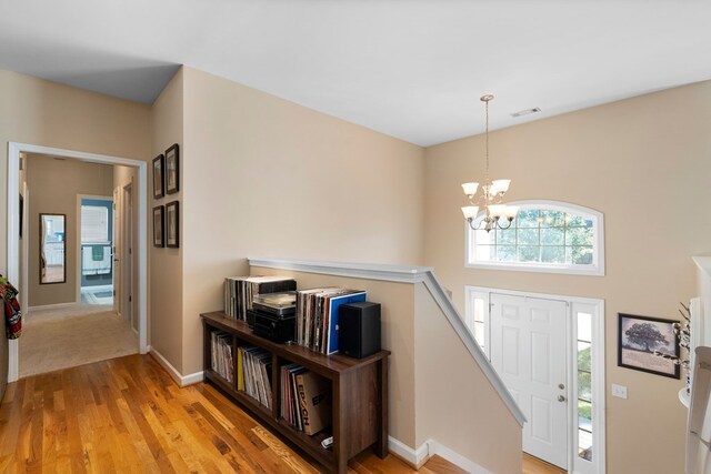 foyer entrance featuring baseboards, light wood-style floors, and an inviting chandelier