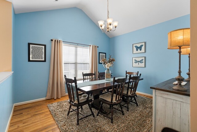 dining space with a chandelier, baseboards, wood finished floors, and vaulted ceiling