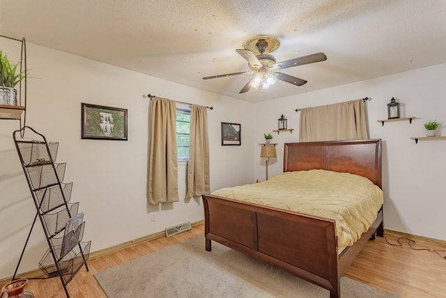 bedroom featuring light wood-type flooring, baseboards, visible vents, and ceiling fan
