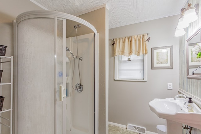 full bath featuring a shower stall, baseboards, a sink, and visible vents