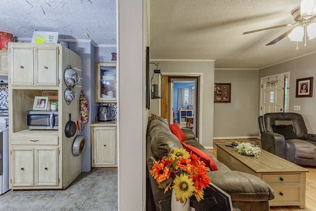 interior space featuring a textured ceiling, stainless steel microwave, open floor plan, ceiling fan, and ornamental molding