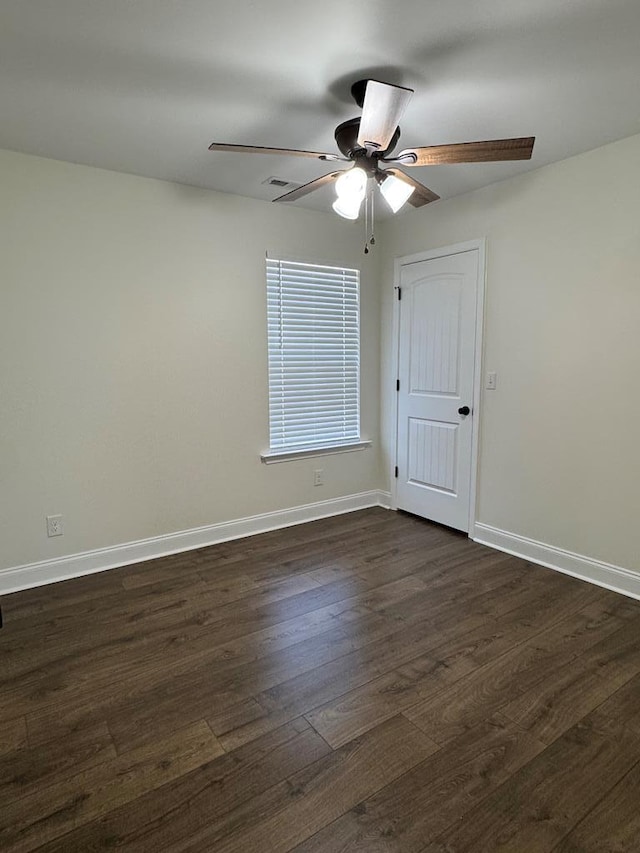 unfurnished room featuring visible vents, dark wood-style flooring, a ceiling fan, and baseboards