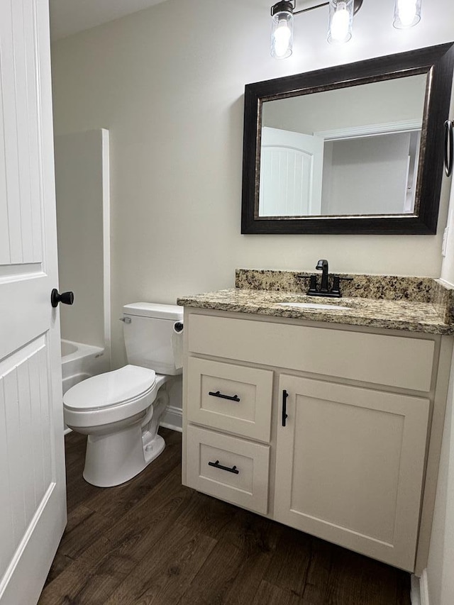 bathroom featuring toilet, shower / bathtub combination, wood finished floors, and vanity