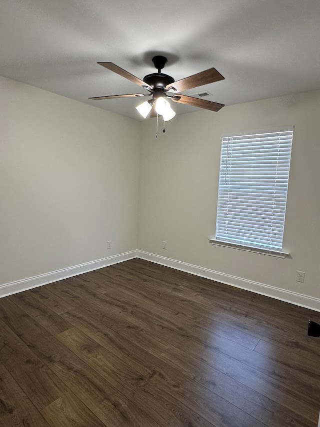 unfurnished room featuring dark wood finished floors, a ceiling fan, and baseboards