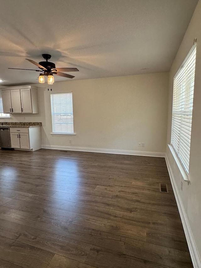 unfurnished living room featuring visible vents, dark wood finished floors, and baseboards