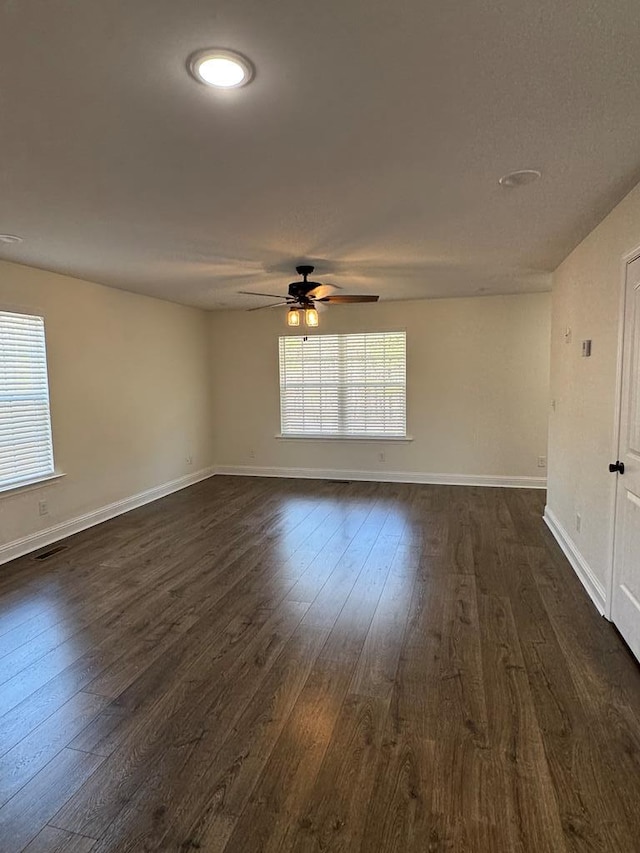 spare room featuring dark wood-type flooring, ceiling fan, and baseboards