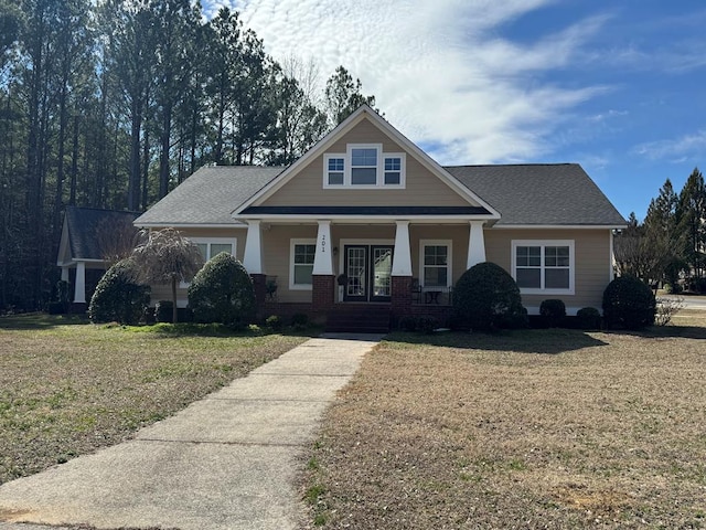 craftsman-style home featuring a front yard, covered porch, and brick siding