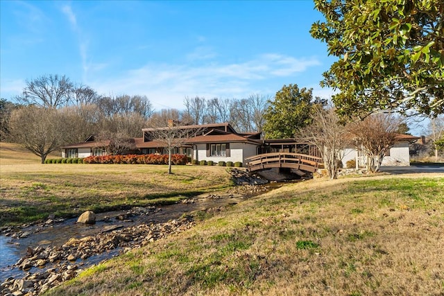 ranch-style house with a deck and a front lawn