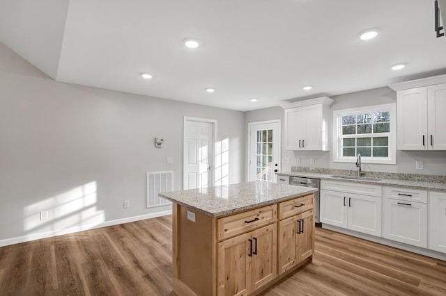 kitchen featuring white cabinetry, a kitchen island, sink, and light stone counters