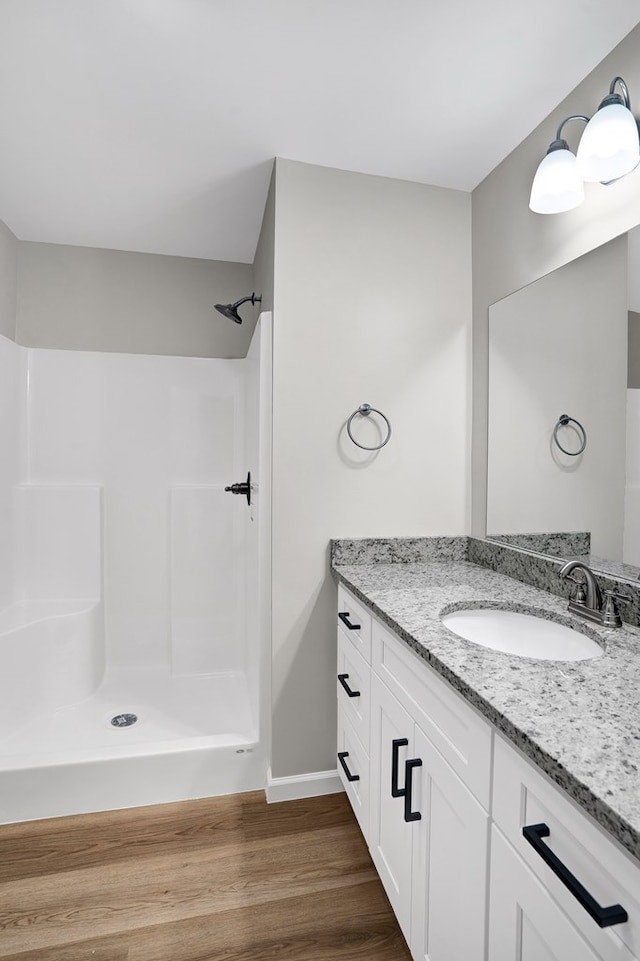 bathroom featuring hardwood / wood-style flooring, vanity, and a shower