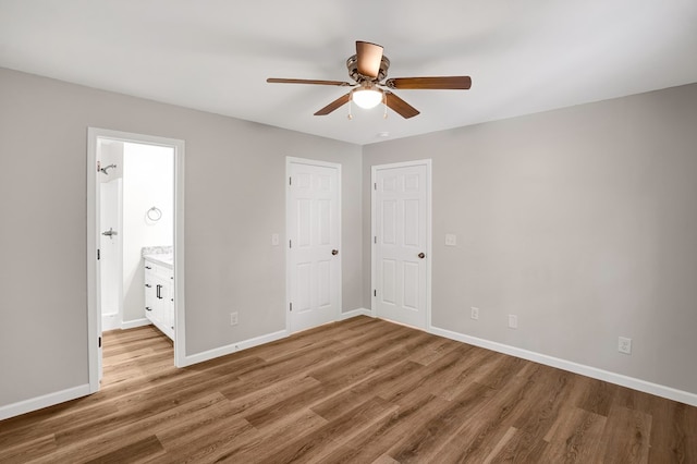 unfurnished bedroom featuring hardwood / wood-style floors, ceiling fan, and ensuite bathroom