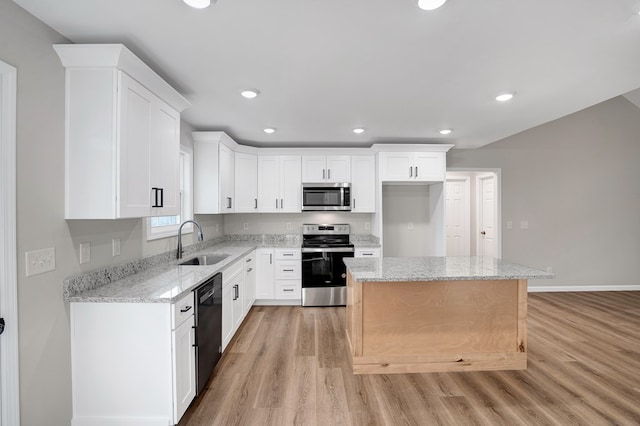 kitchen featuring appliances with stainless steel finishes, sink, white cabinets, a center island, and light stone countertops