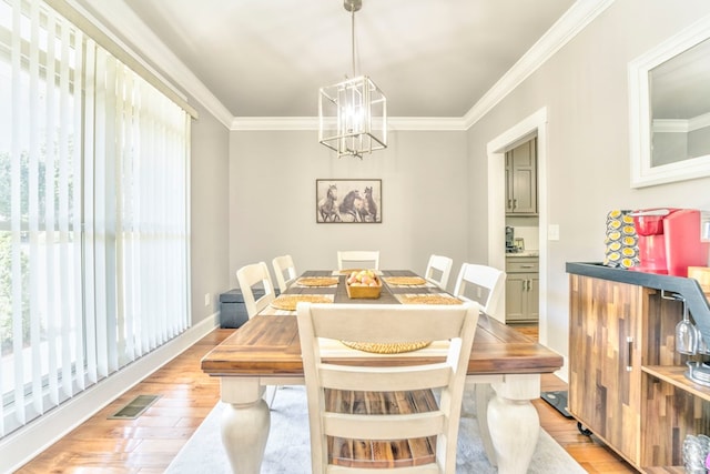 dining room with an inviting chandelier, ornamental molding, and light wood-type flooring