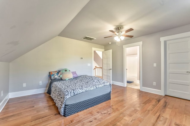 bedroom with hardwood / wood-style flooring, ceiling fan, vaulted ceiling, and ensuite bath