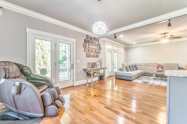 living room featuring ceiling fan with notable chandelier, ornamental molding, light hardwood / wood-style floors, and french doors