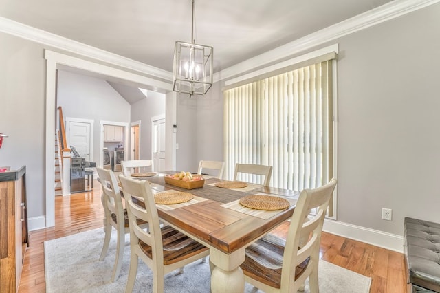 dining room with crown molding, separate washer and dryer, an inviting chandelier, and light wood-type flooring