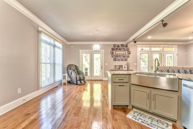 kitchen featuring sink, crown molding, light hardwood / wood-style flooring, light stone counters, and stainless steel dishwasher