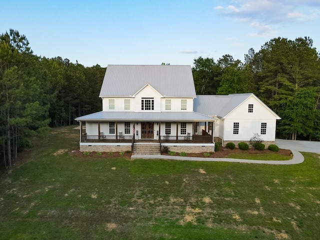 view of front facade featuring metal roof, a porch, a forest view, and a front lawn