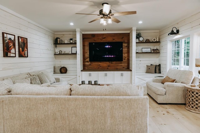 living area featuring light wood-style floors, wooden walls, a ceiling fan, and recessed lighting