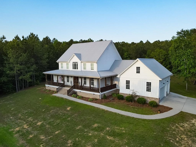 view of front of property featuring covered porch, a wooded view, a front lawn, and driveway