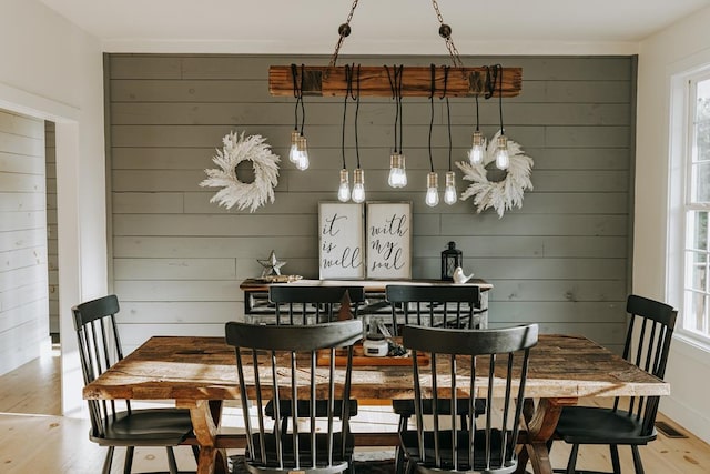 dining room with wood walls, plenty of natural light, and light wood-style floors