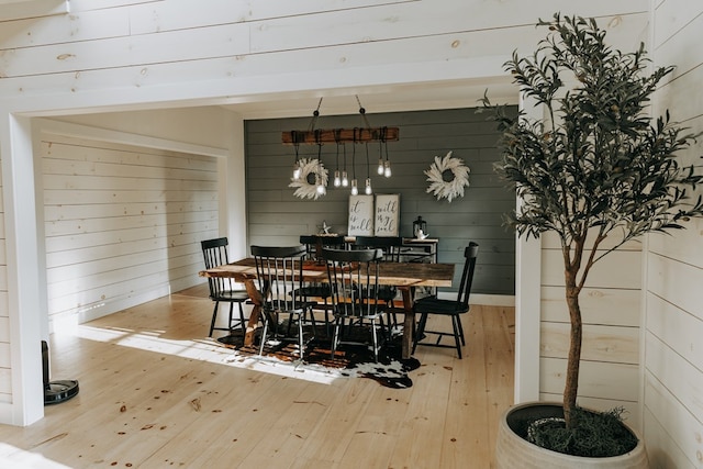 dining area with wood walls and hardwood / wood-style floors