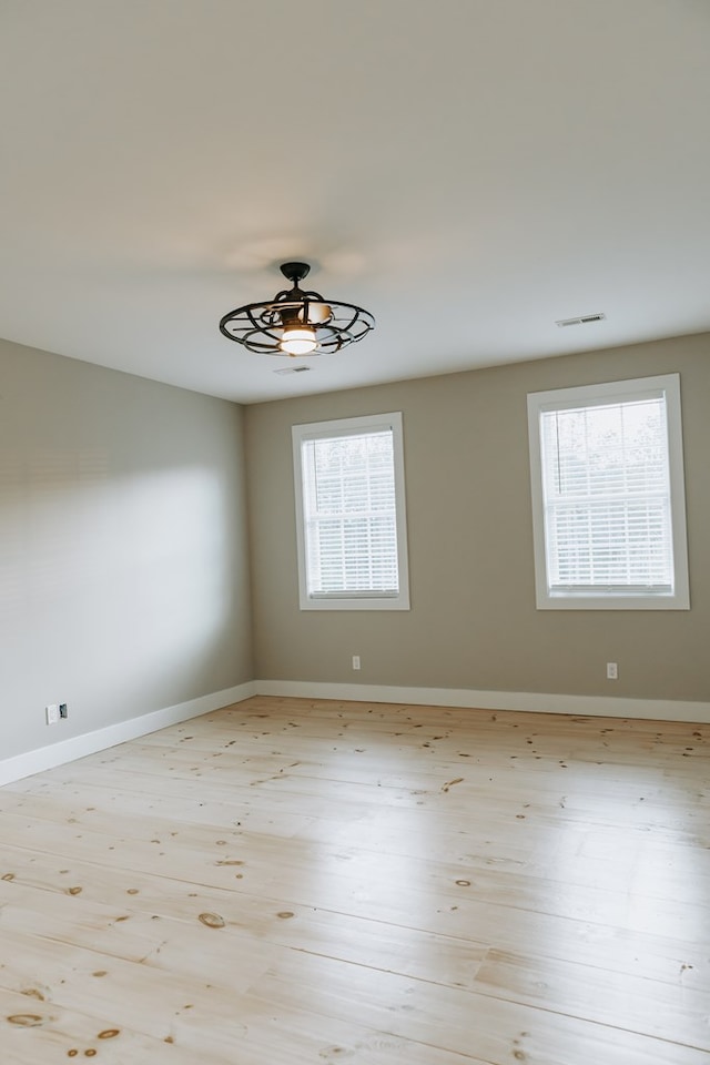 spare room featuring baseboards, visible vents, ceiling fan, and wood finished floors