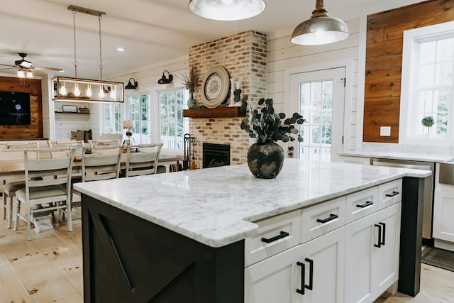 kitchen featuring a center island, light stone counters, a ceiling fan, and open floor plan