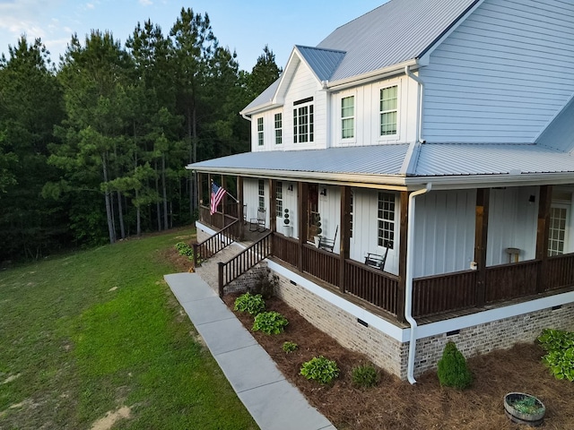 view of front of property with covered porch, crawl space, a front lawn, and metal roof