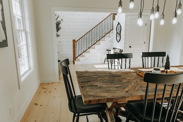 dining space featuring stairs, baseboards, and light wood-type flooring