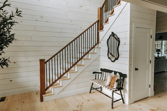 stairs featuring wooden walls and wood-type flooring