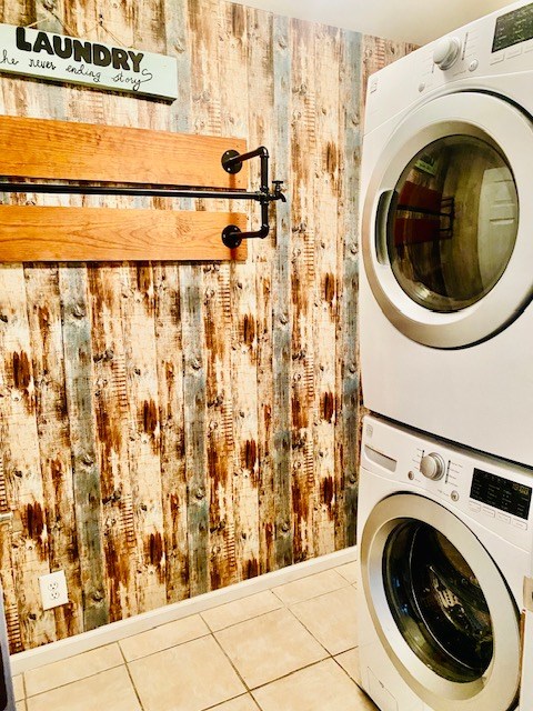 washroom featuring stacked washer and clothes dryer and tile patterned flooring