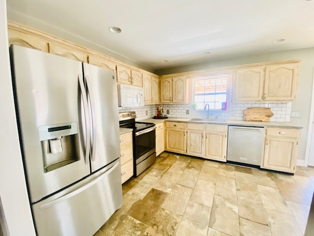 kitchen with tasteful backsplash, appliances with stainless steel finishes, sink, and light brown cabinetry