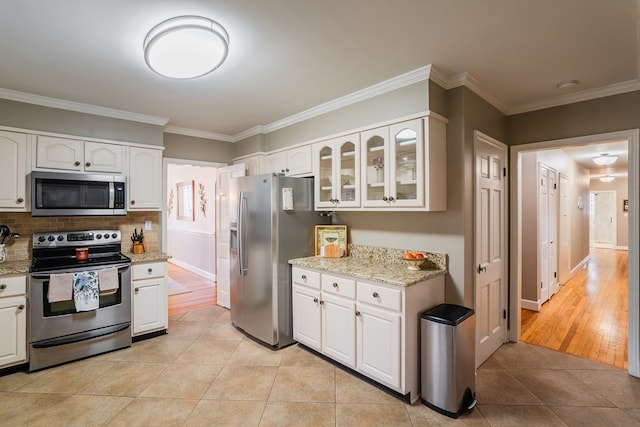 kitchen featuring white cabinetry, ornamental molding, appliances with stainless steel finishes, and light stone countertops