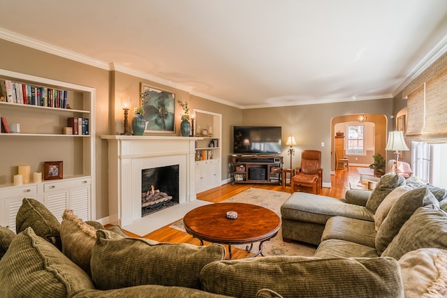 living room featuring ornamental molding, built in features, and light wood-type flooring